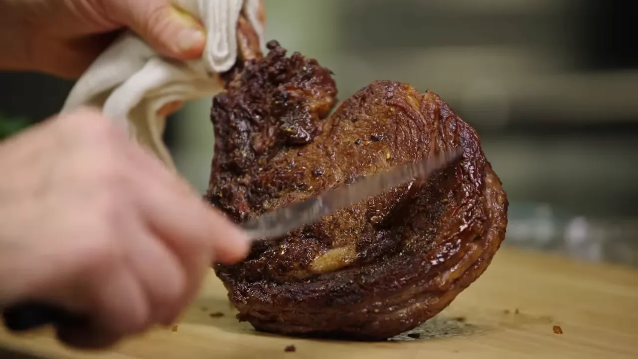 Knife slicing through a thick, seared steak on a wooden board