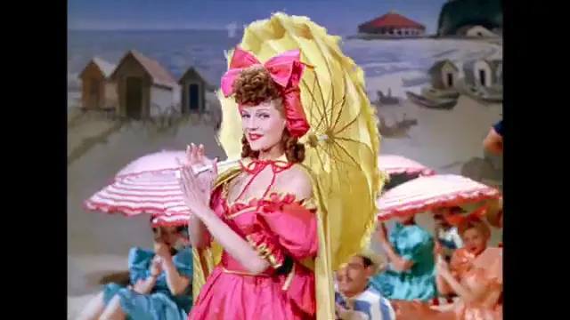 Rita Hayworth performing a beach-themed musical number with parasol and chorus