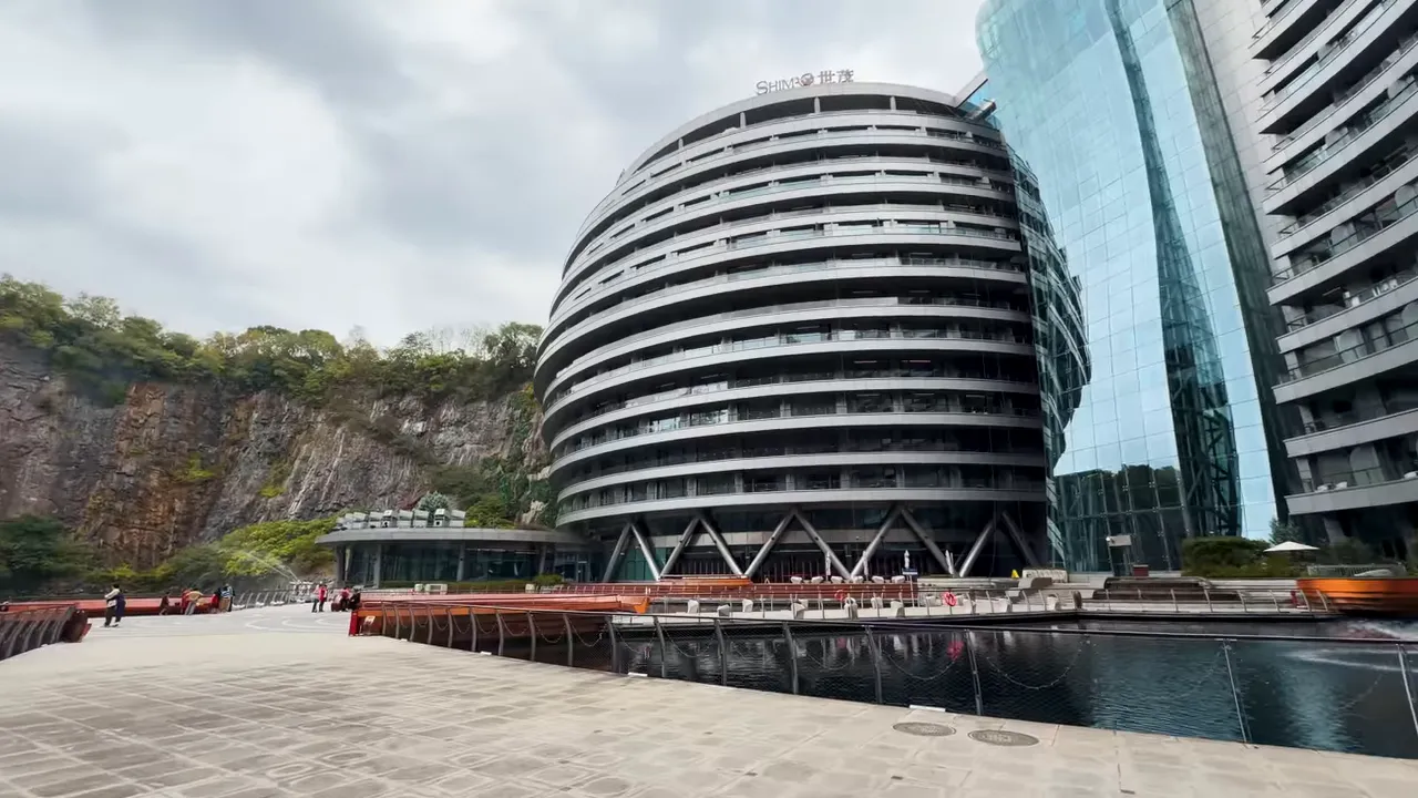 Curved hotel built into a quarry with rock walls and water in front
