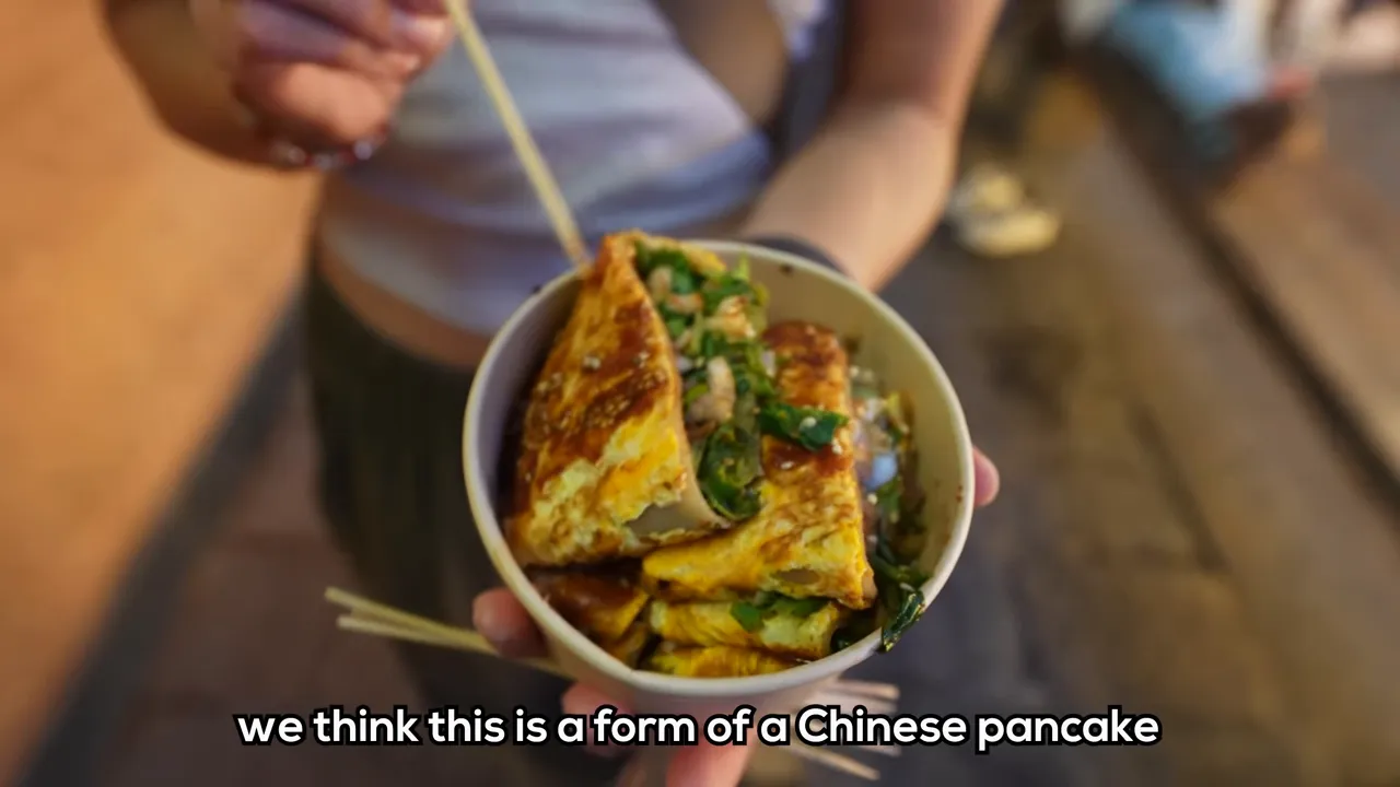 Bowl of savory pancake pieces with greens and sauce held above a food stall