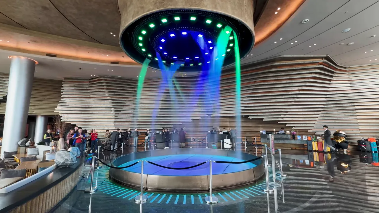 Lobby water feature forming shapes beneath a circular ceiling installation