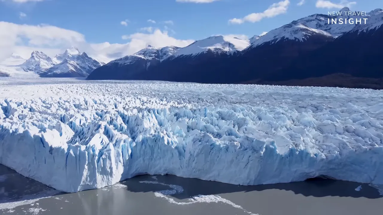 Panoramic view of a glacier tongue and ice cliffs stretching across a mountain valley