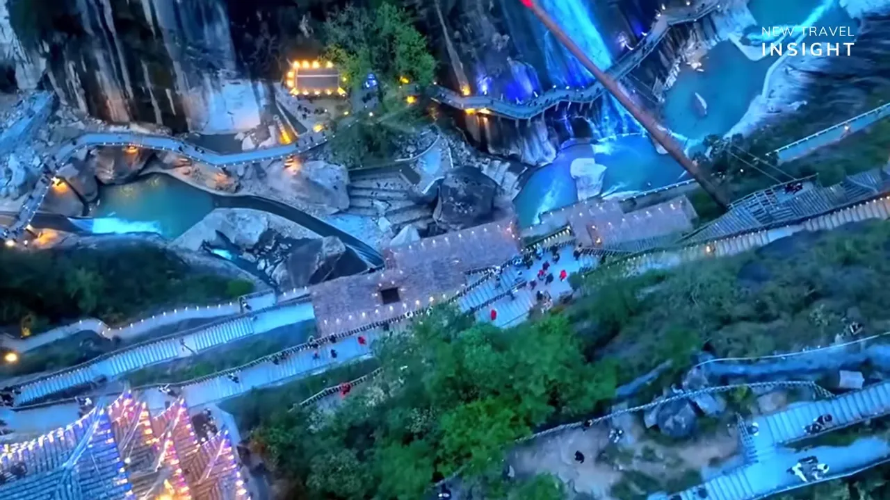 Night aerial view of illuminated walkway and river through a rocky canyon