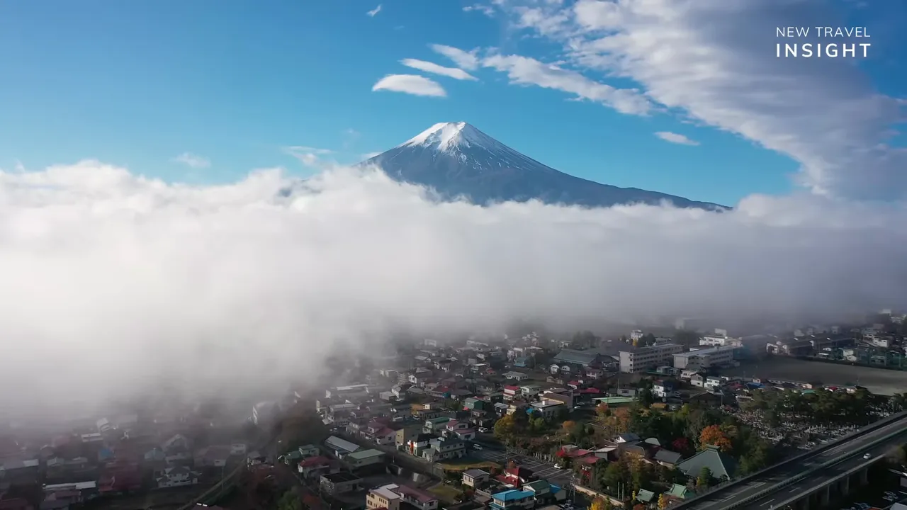 Mount Fuji with snowy peak above clouds and rooftops