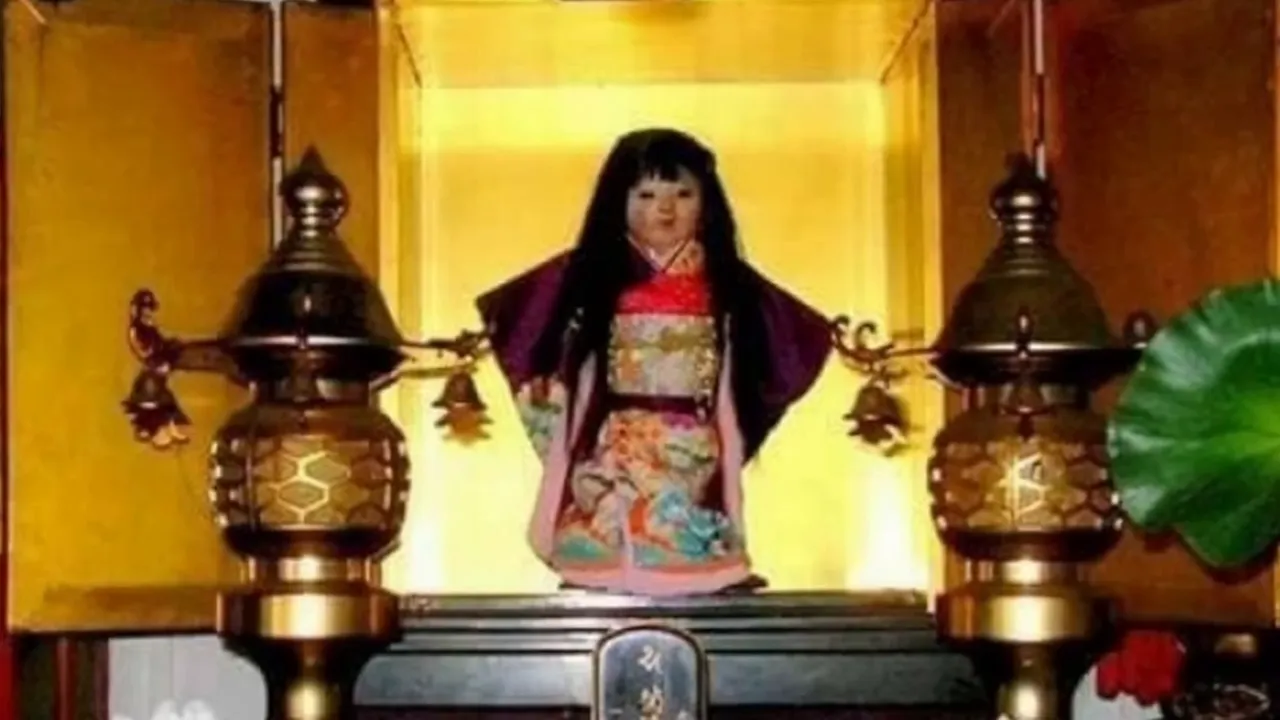 Japanese doll with long black hair on a golden altar between two brass lamps