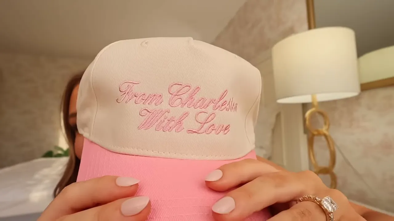 Pink and white embroidered baseball cap held close to the camera