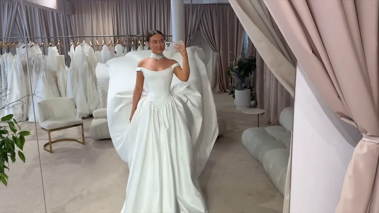 Bride trying on a strapless satin ball gown in a bridal showroom