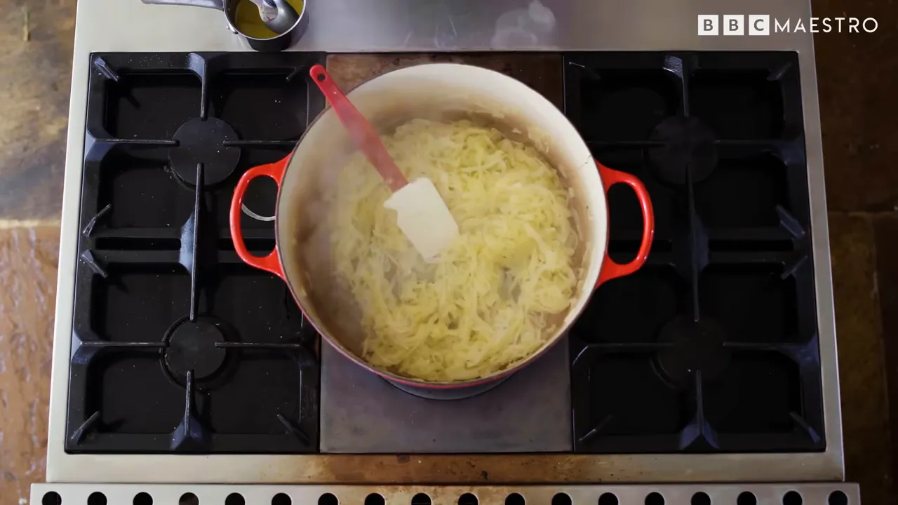 Potatoes and butter in a pot on a stovetop for pommes boulangère