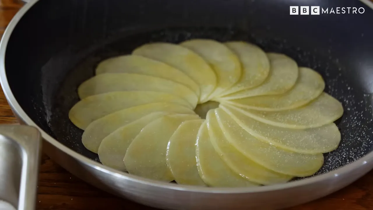 Overlapping butter-coated potato slices in a pan for pommes Maxim