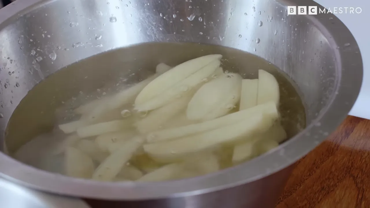 Potato chips blanching in water in a large pot