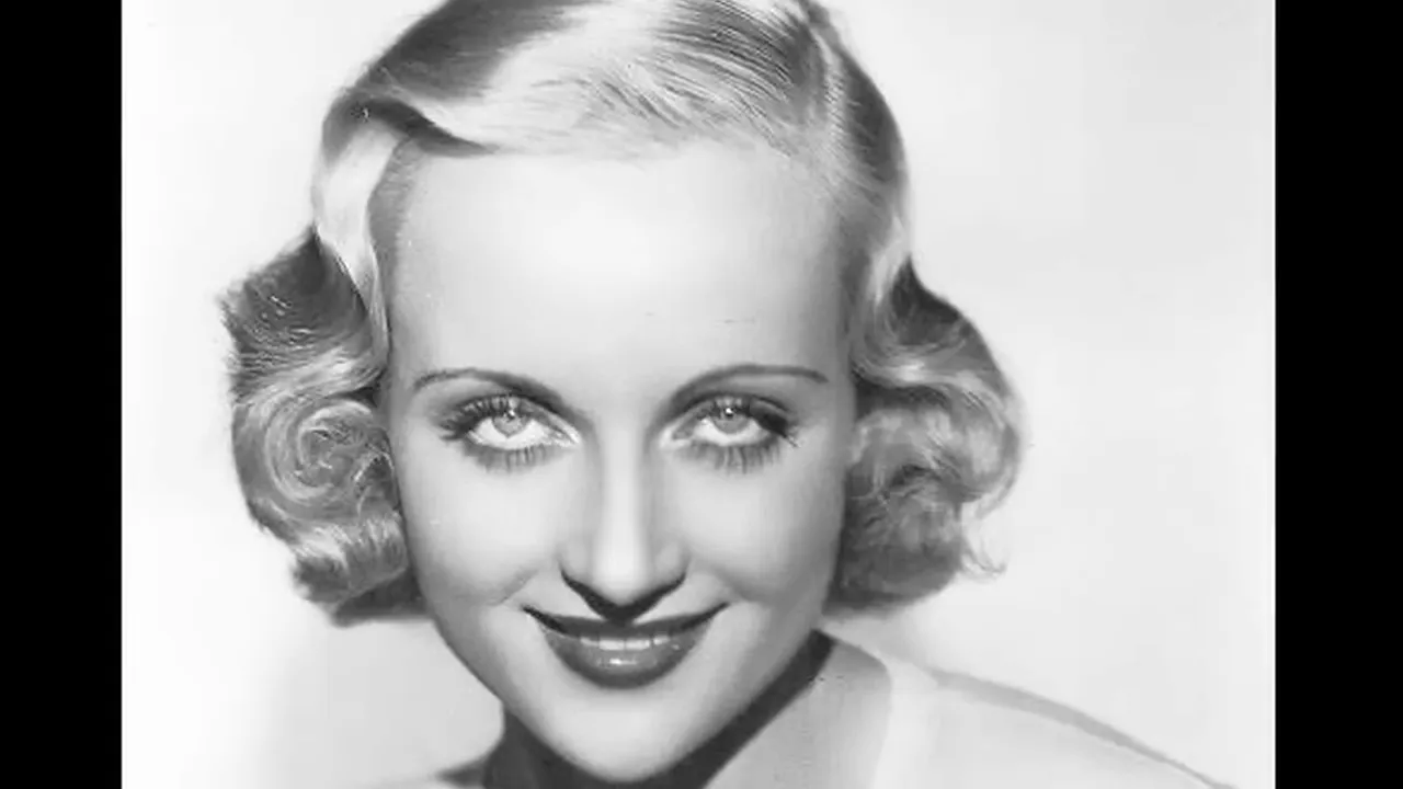 Studio head-and-shoulders portrait of Carole Lombard, smiling with waved blonde hair
