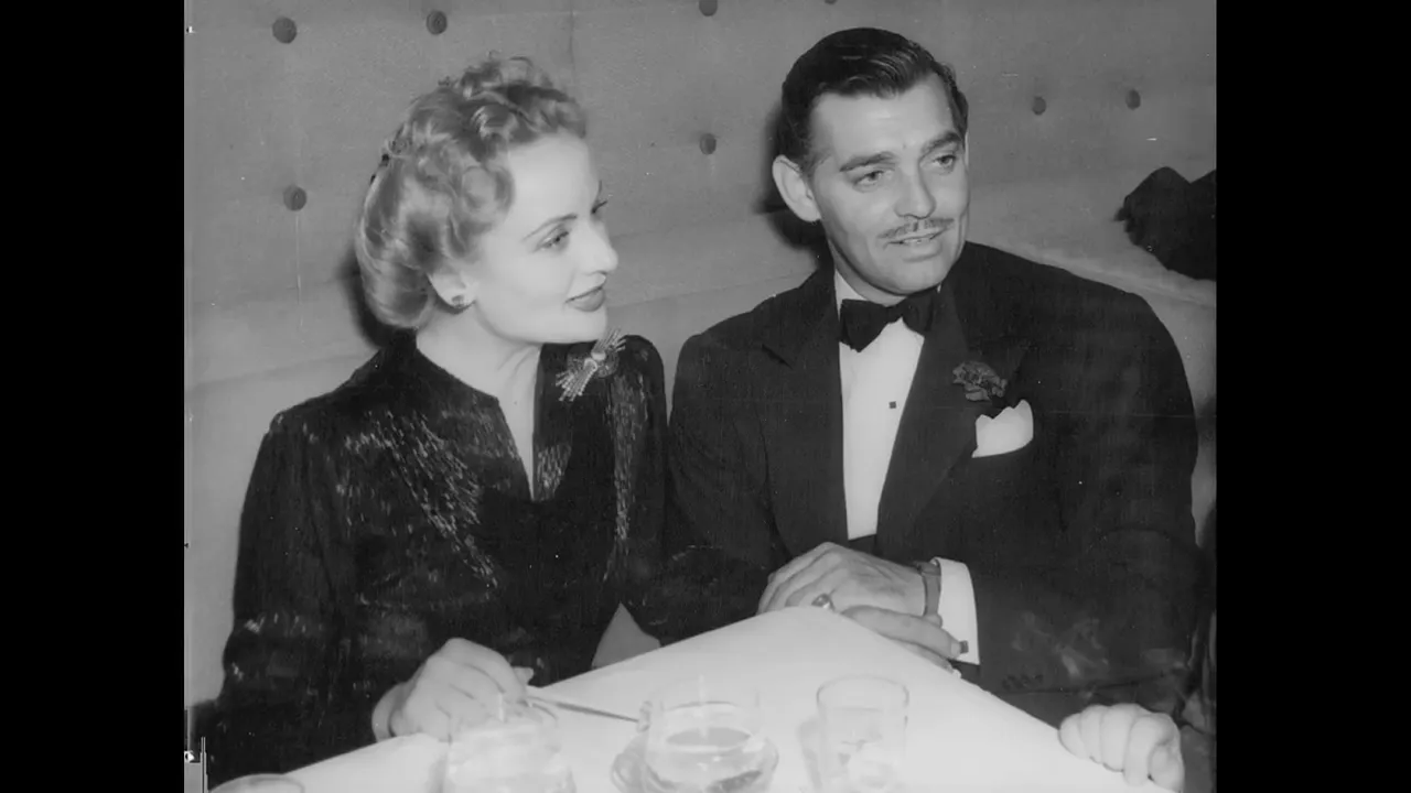 Black-and-white formal portrait of a woman and a man seated together at a table, dressed in evening wear