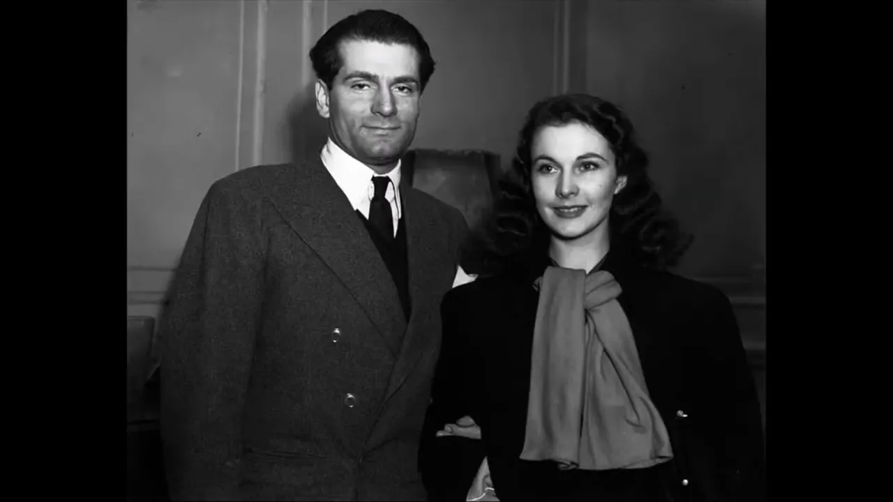 Black-and-white public-appearance portrait of an actress and a male companion standing together in formal attire.