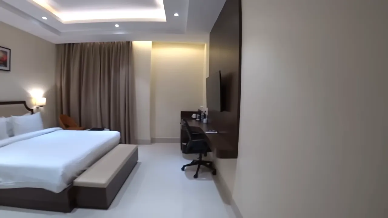 Clean hotel room interior with bed, curtains, and desk area