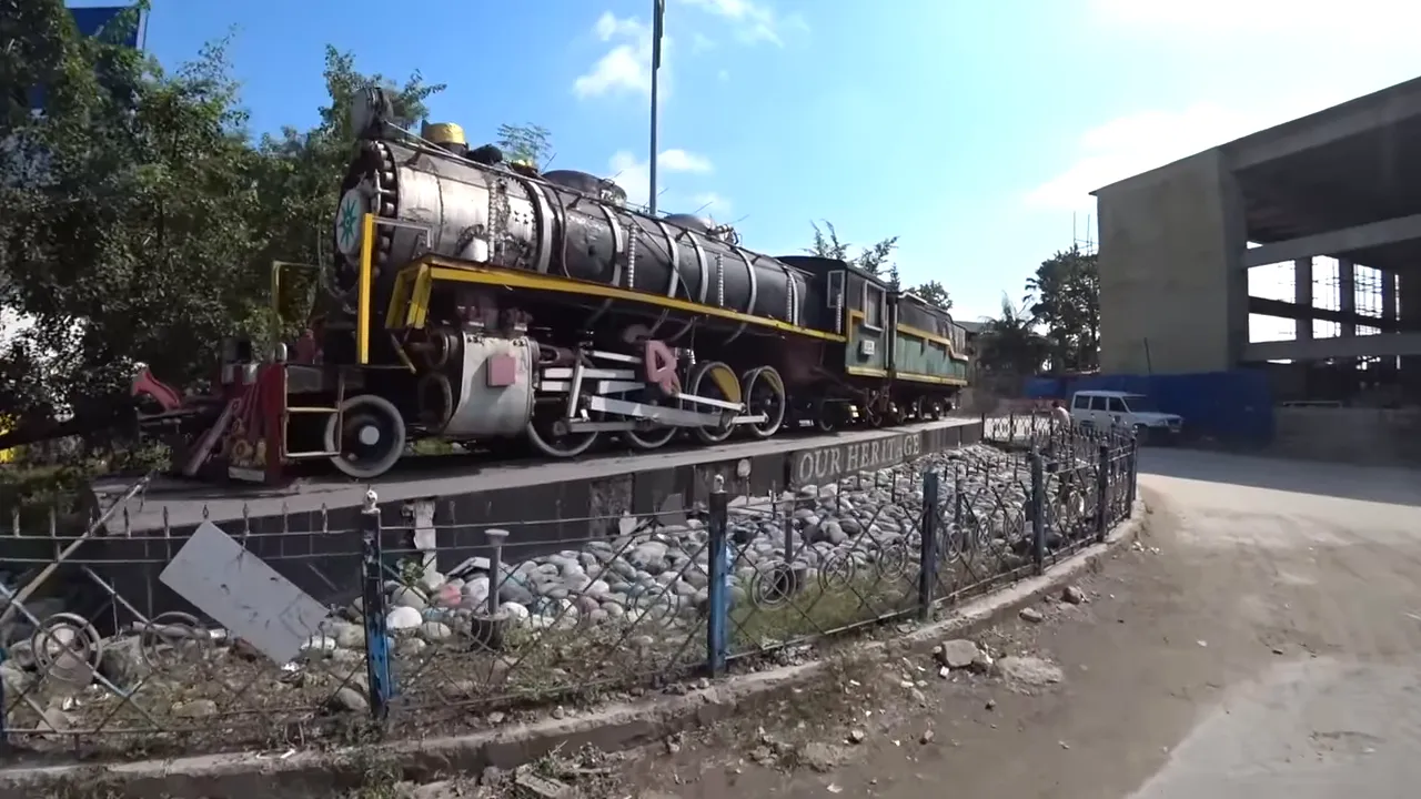 Close-up of a historic steam locomotive displayed beside an Indian railway platform