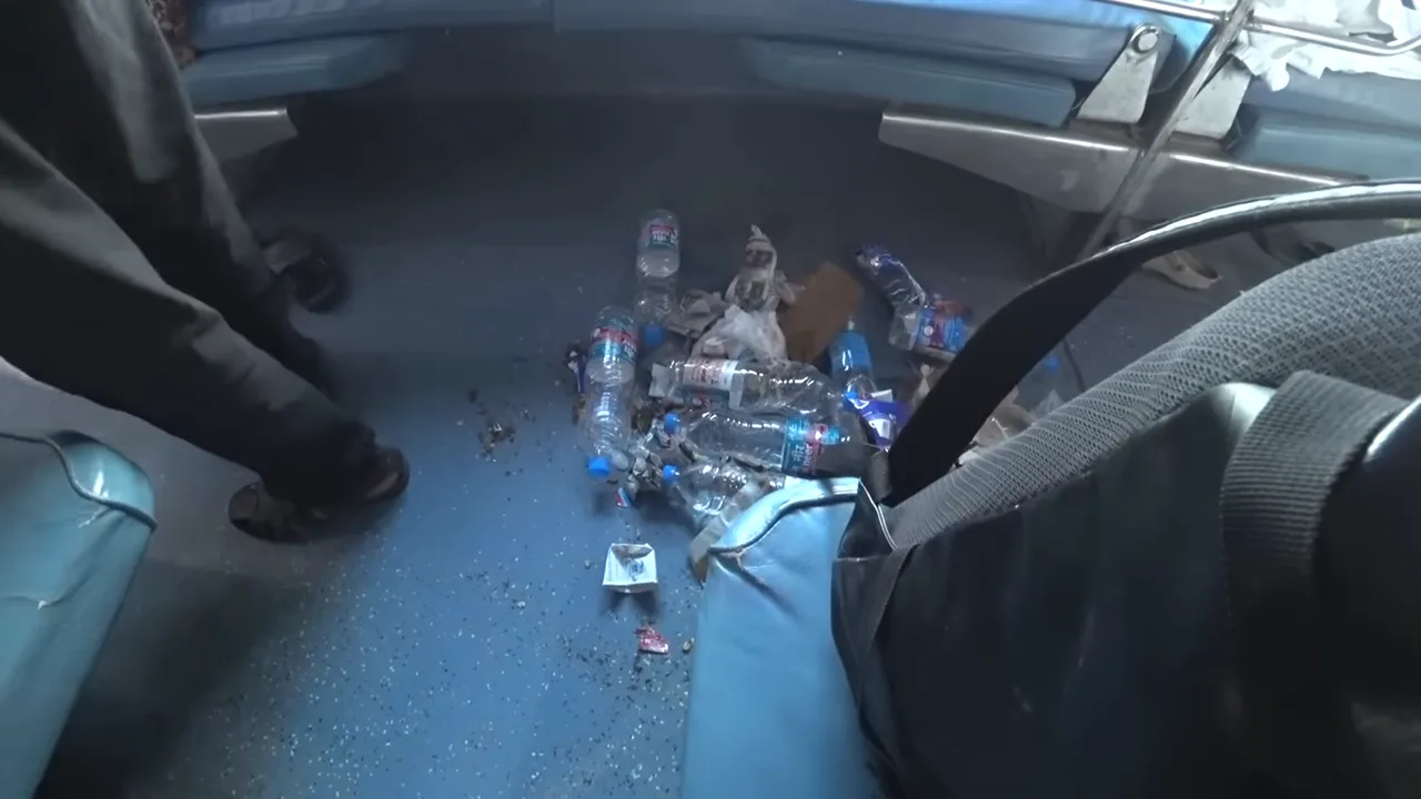 View of the floor of a train compartment covered with scattered bottles and trash
