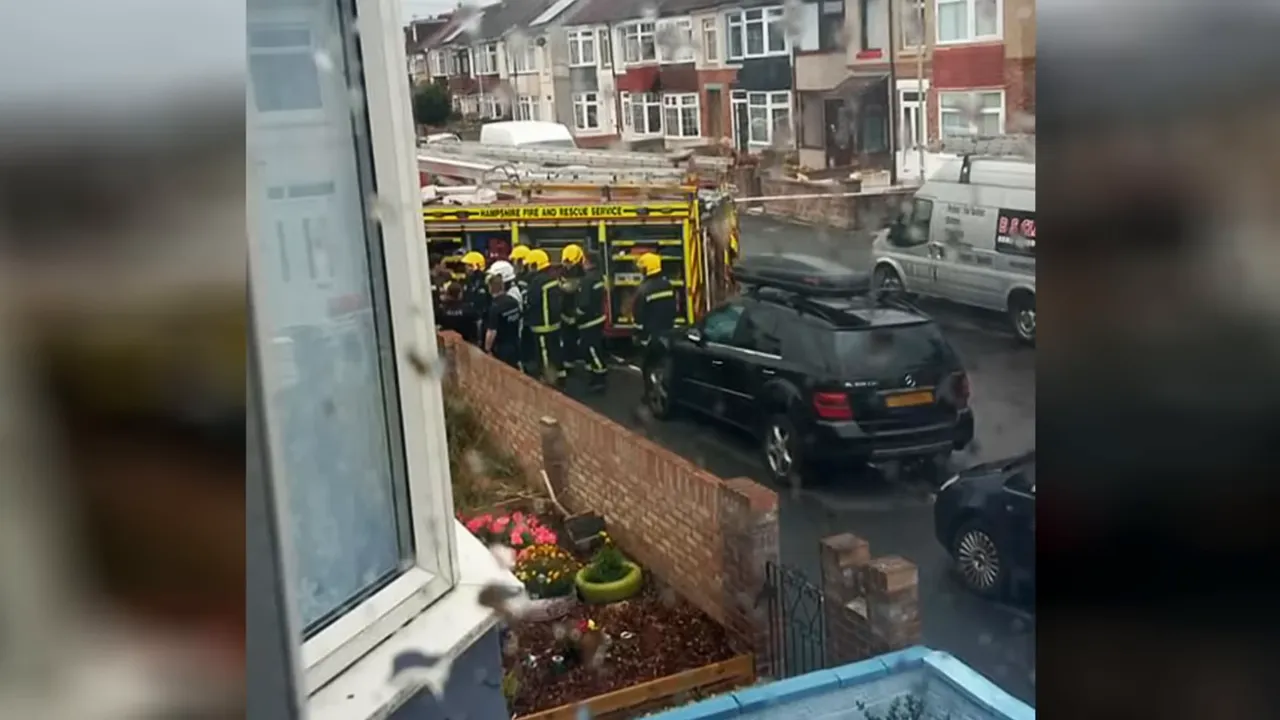 Firefighters at a terraced house with smoke, police tape beginning to appear