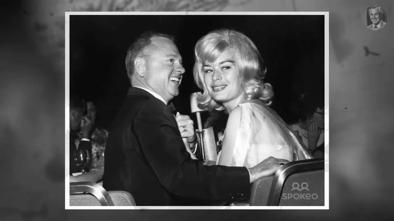 Crisp black-and-white archival photo of an older man and a blonde woman seated together at a public event