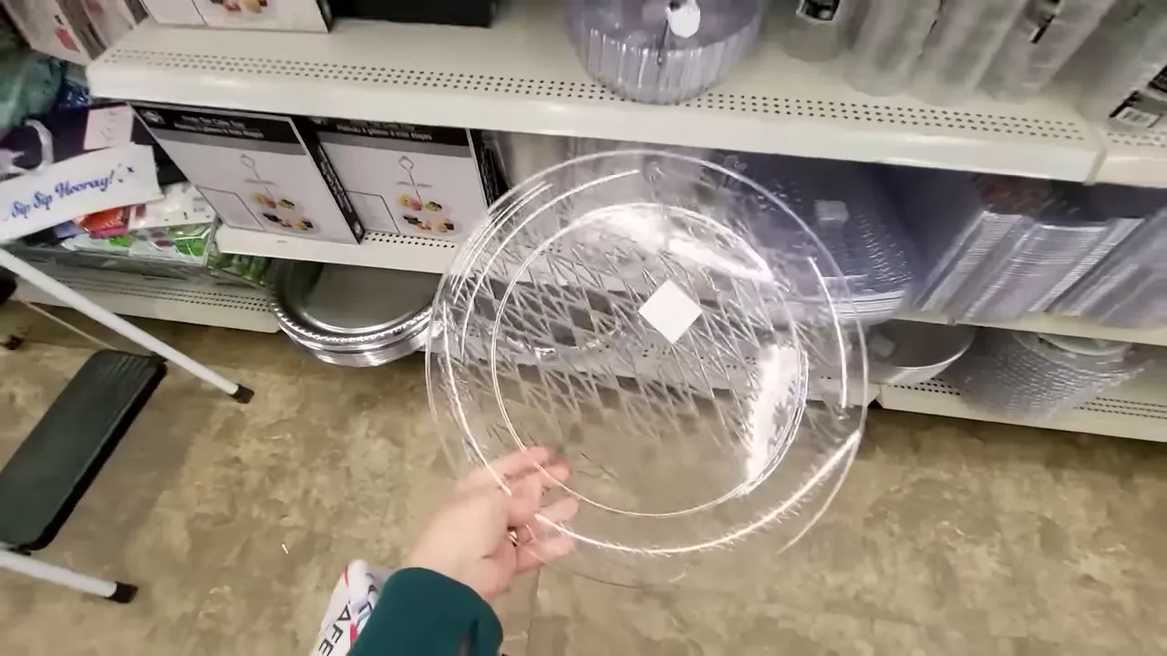 Hand holding a clear plastic party tray in a store aisle, showing size and shape of the tray