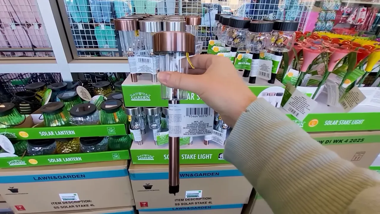 Hand holding a copper-top solar stake light in a store aisle with multiple solar garden lights on display