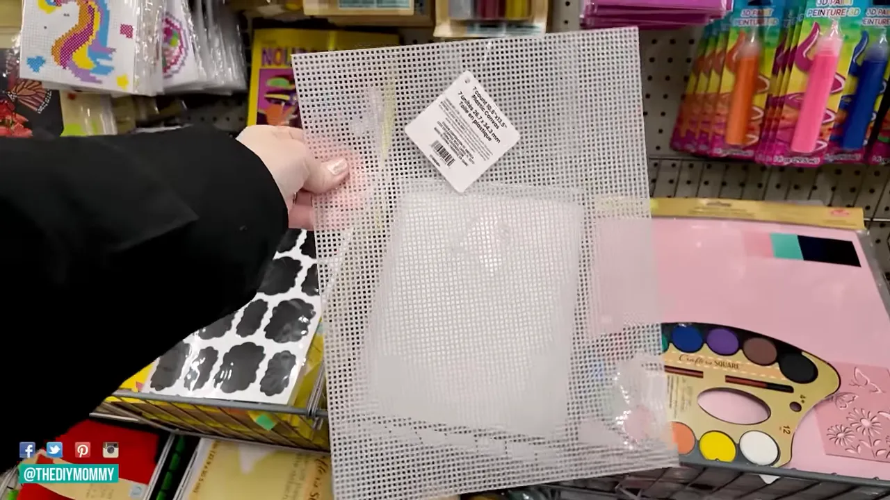 Hand holding a white plastic mesh grid sheet with a product tag in a craft store aisle