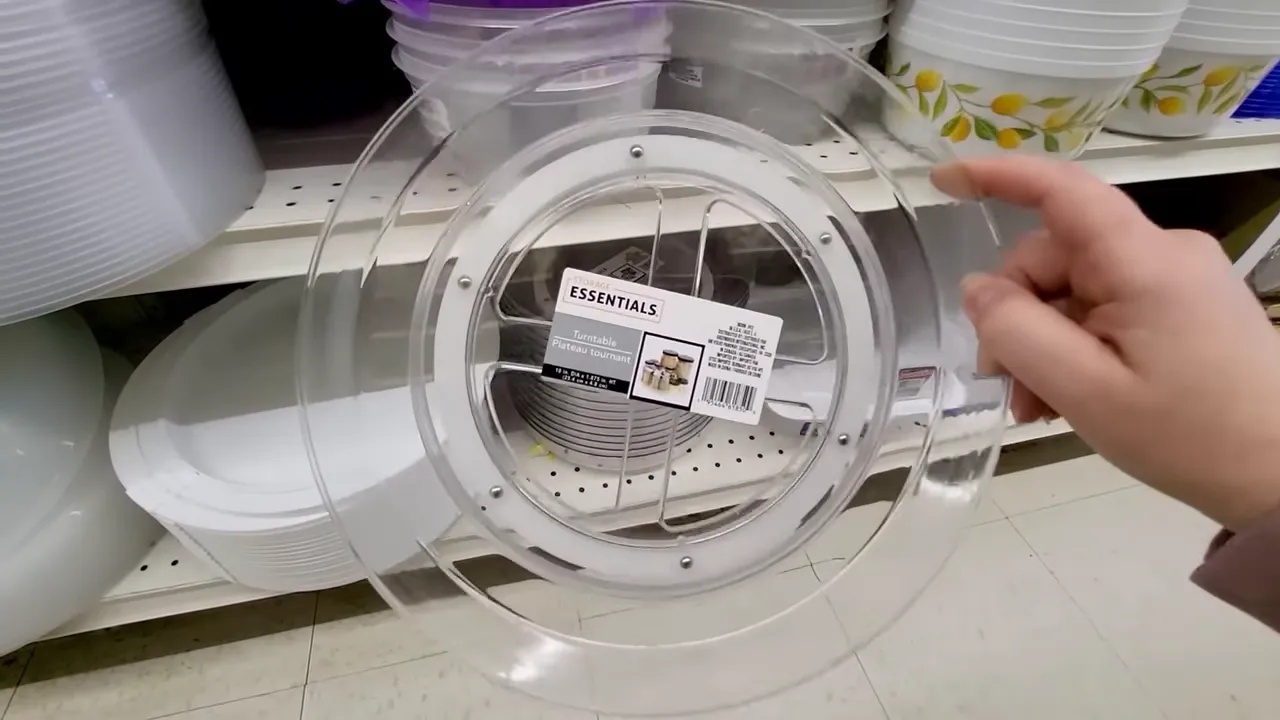 Hand holding a clear plastic countertop turntable in a store aisle