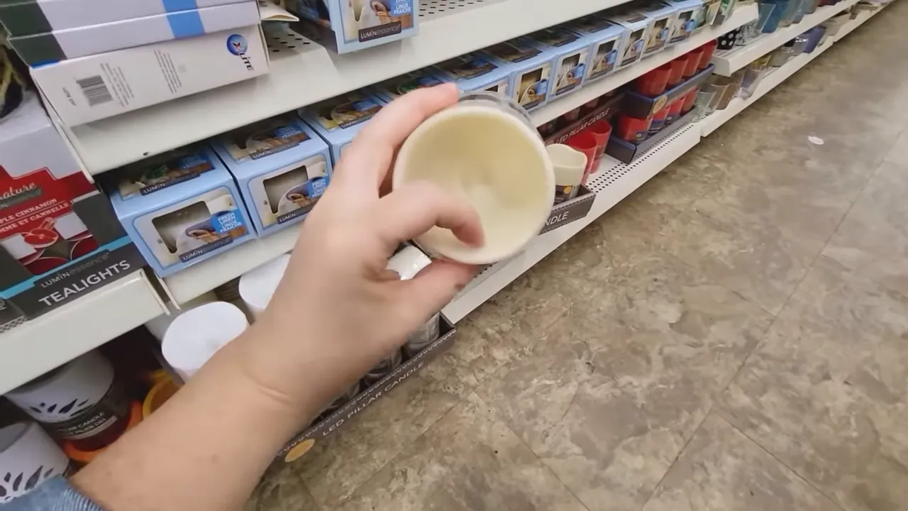Close-up of hand holding a cream wax-coated battery LED candle showing the wax surface and interior