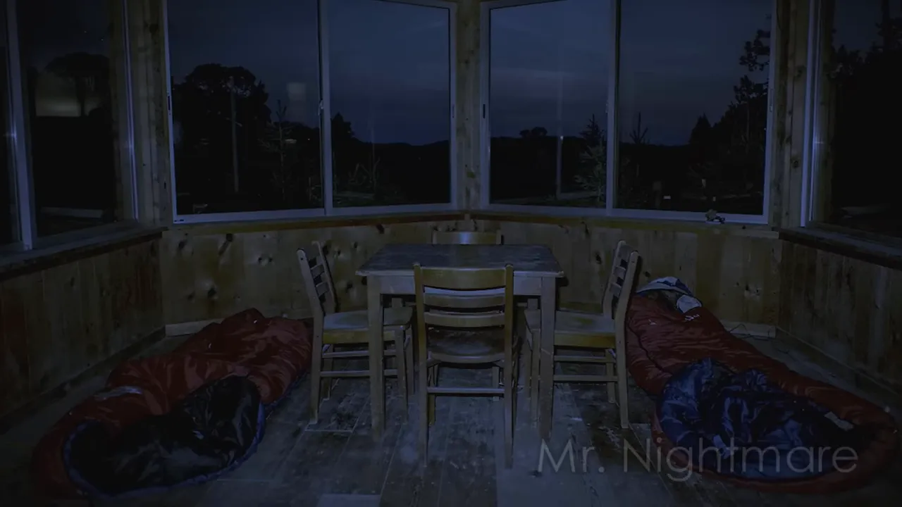 Night interior of an abandoned fire lookout tower showing sleeping bags and large windows
