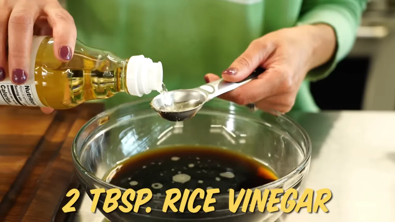 Rice vinegar being measured into a glass bowl of dark stir-fry sauce