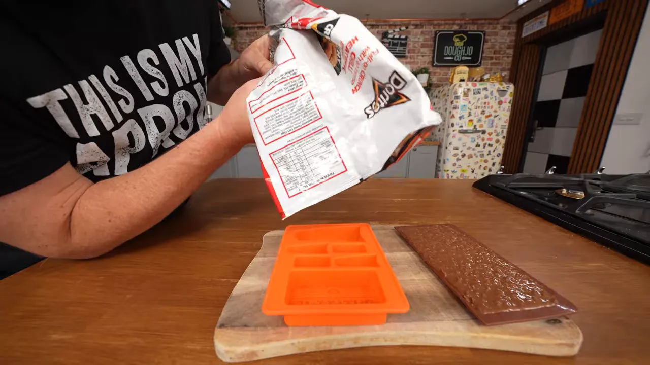 Chocolate and crushed Dorito mixture being poured into an orange mould