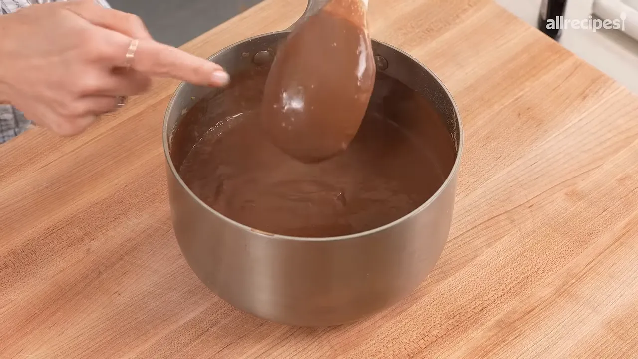 Thick chocolate pie filling coating the back of a wooden spoon over a saucepan