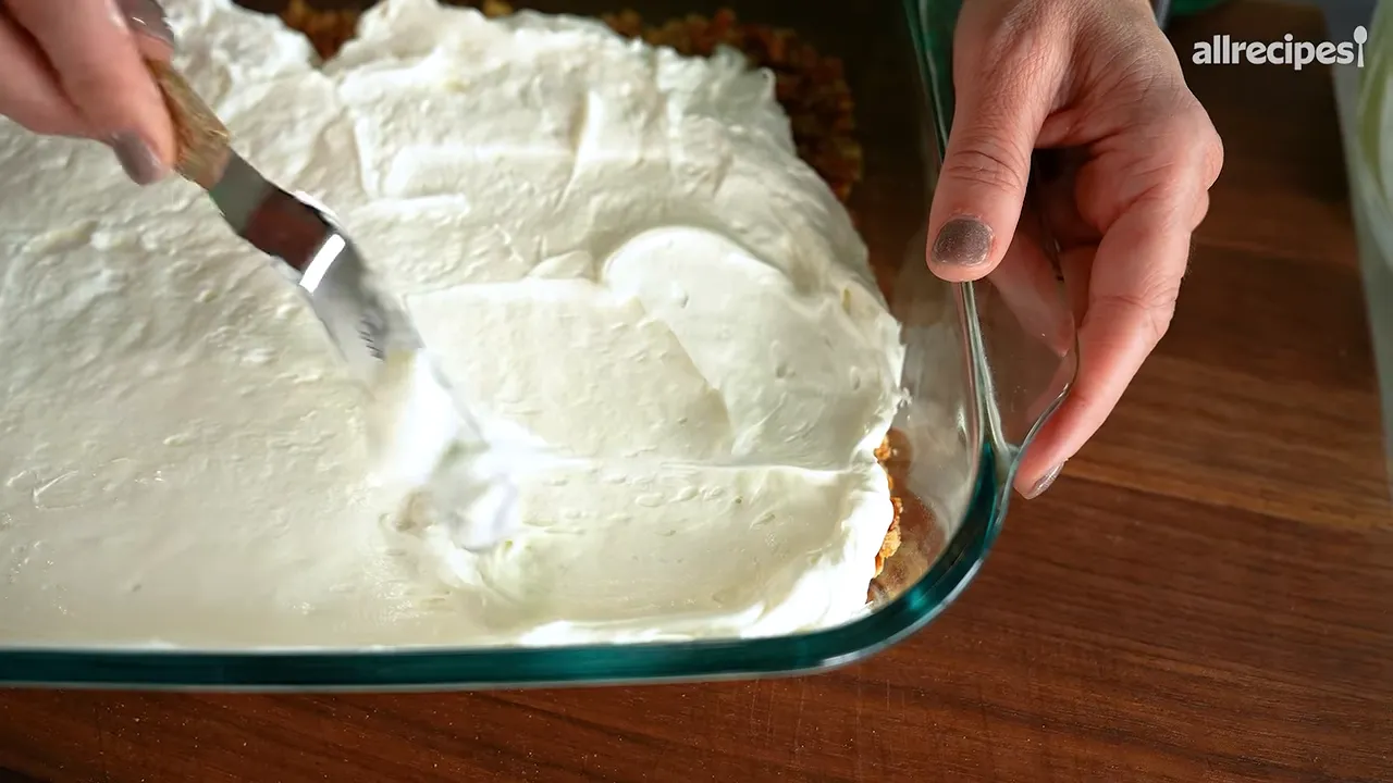 Cream cheese filling spread to the edges of a glass dish over a pretzel crust