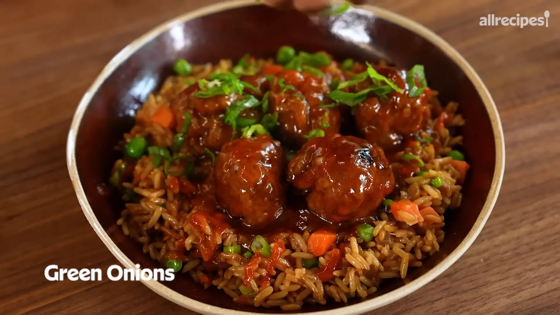 Sweet and sour meatballs glazed in sauce with green onions