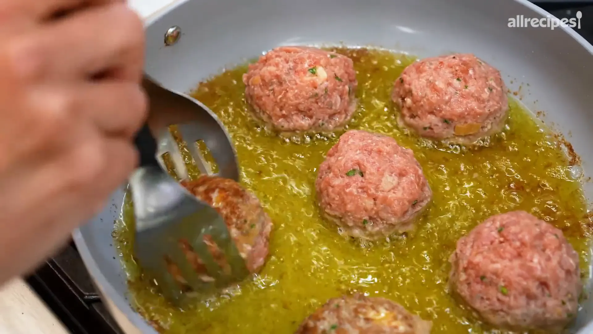 Frying large Italian meatballs in olive oil