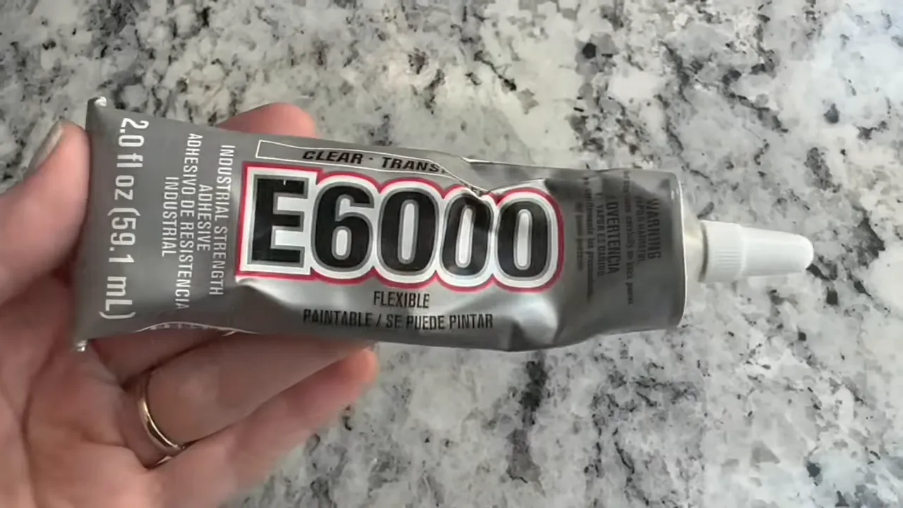 Tube of E6000 industrial-strength adhesive held over a marbled countertop