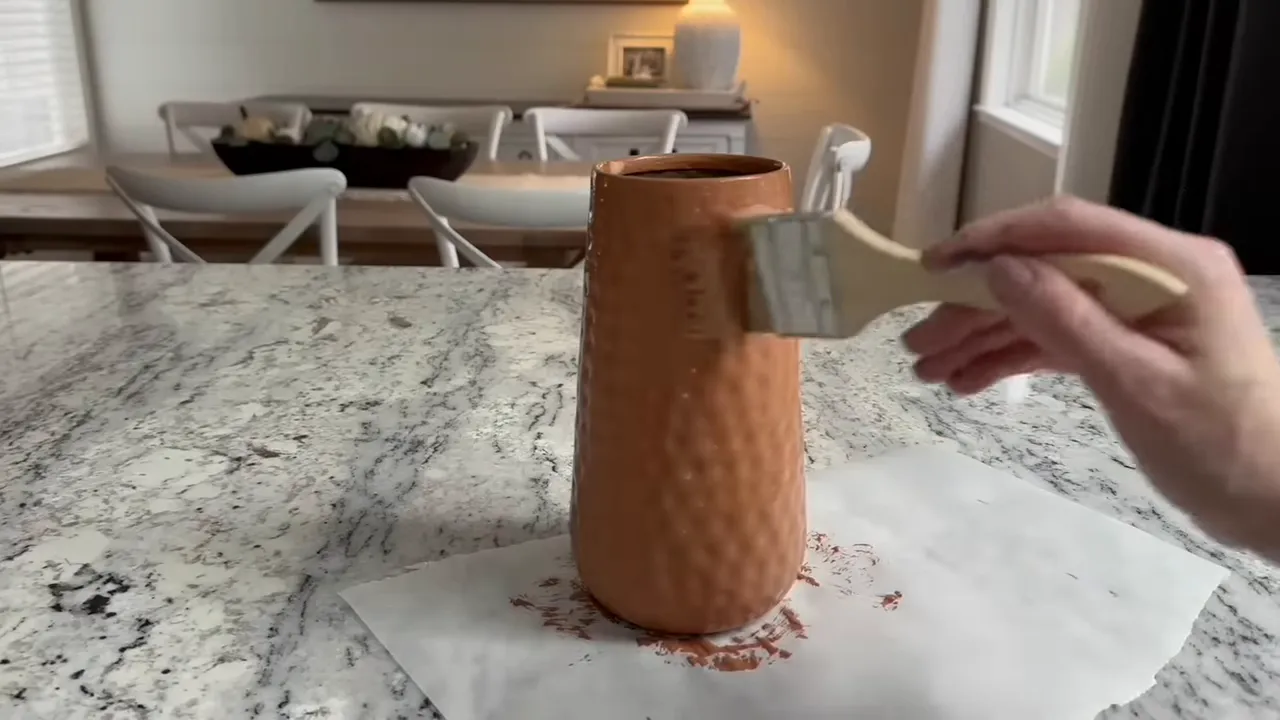 hand brushing paint onto a textured vase preparing a two-tone finish