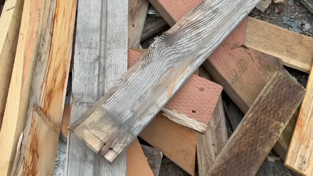 pile of reclaimed fence boards and scrap lumber showing grain, nail holes, and varied finishes
