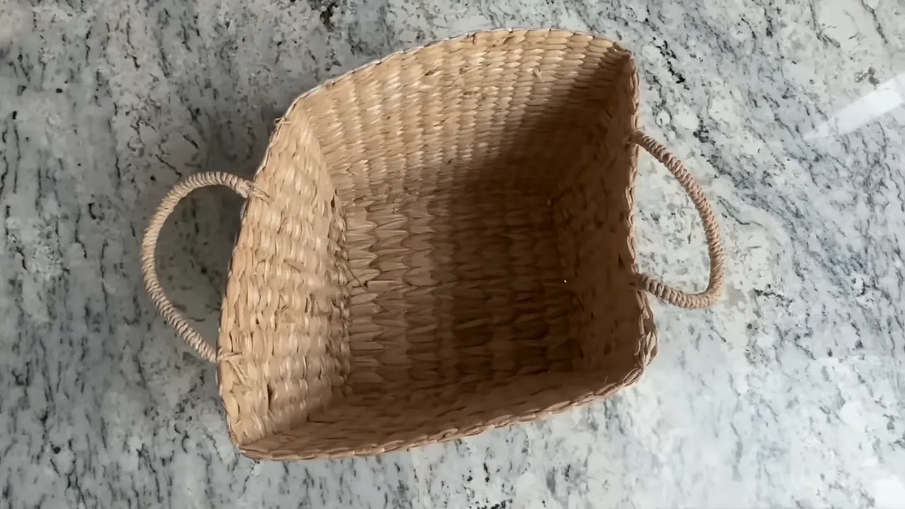 top-down view into a rectangular woven basket showing interior weave and rope handles on a marble countertop