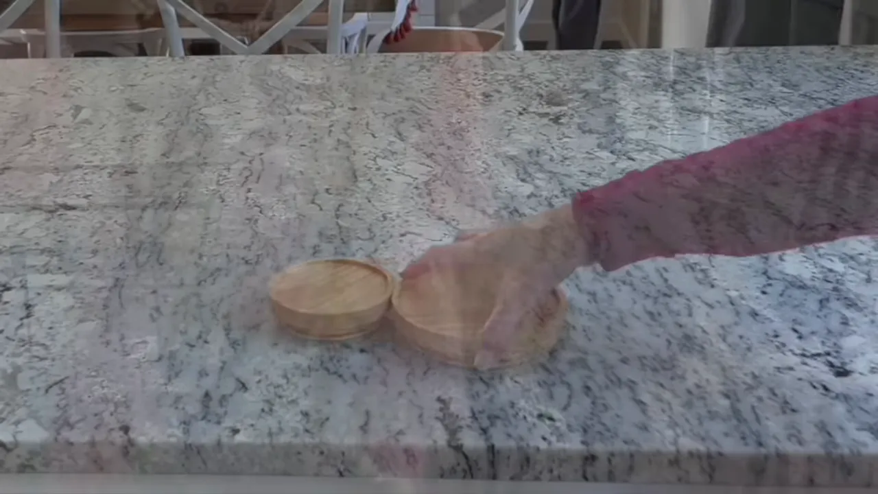 two small wooden discs on a granite countertop with a hand reaching to arrange them