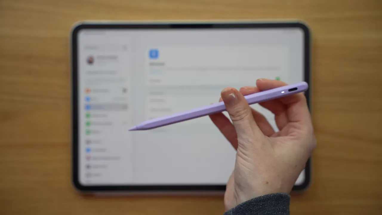 Hand holding a purple stylus over an iPad screen showing documents