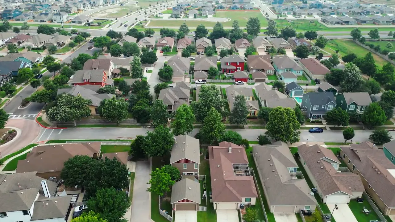 Aerial view of an Austin-area suburb showing homes, fences, and tree-lined roads