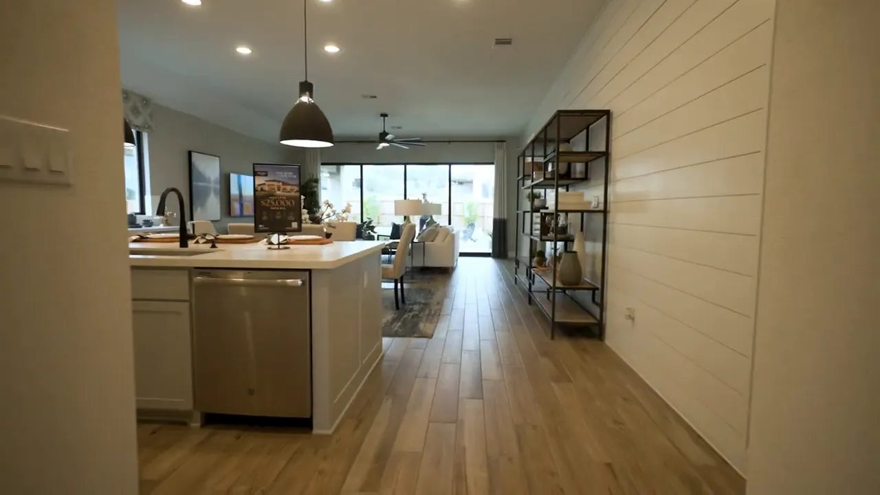 Open kitchen and living room in a western Buda TX model home with island and large windows