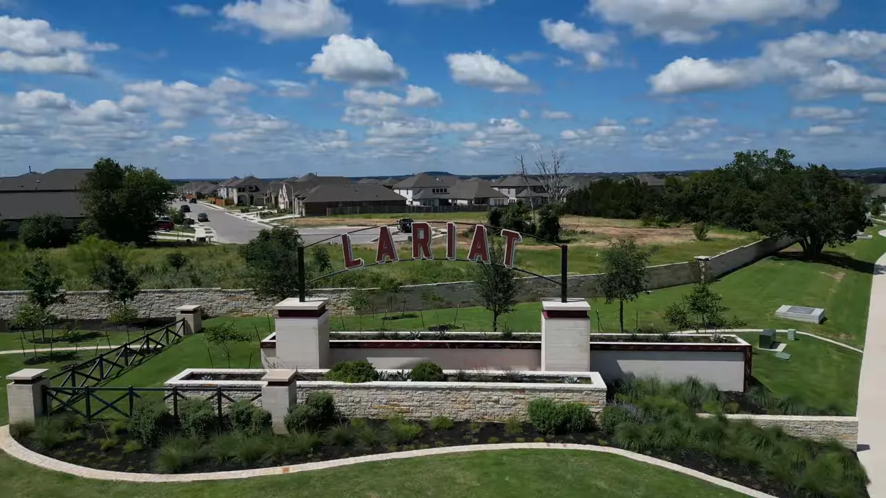 Entrance monument displaying the name Lariat beside landscaped paths