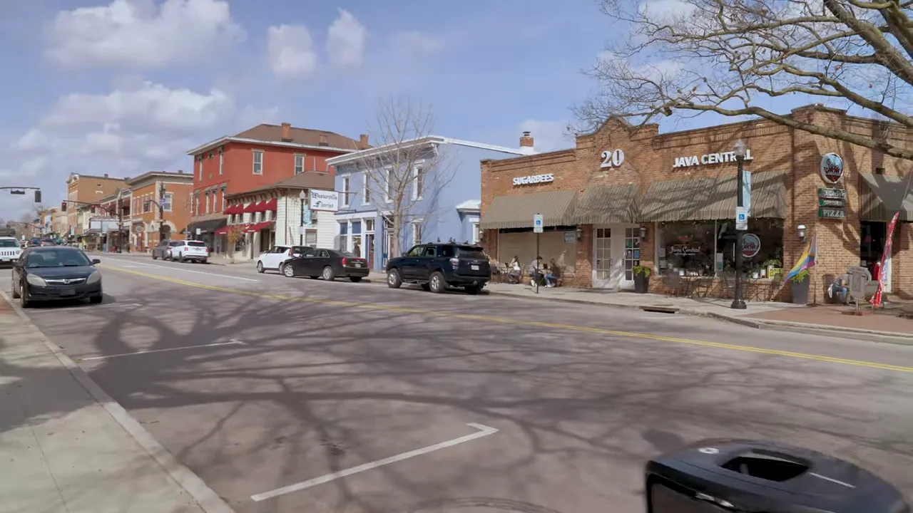 Downtown street with brick storefronts parked cars and wide roadway