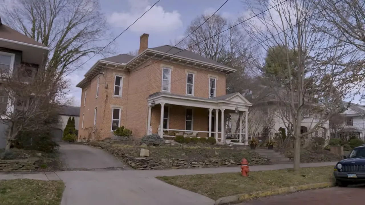 Older brick house with front porch and driveway in established neighborhood