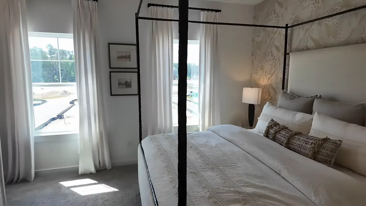 Primary bedroom with canopy bed wallpaper accent wall and tall windows