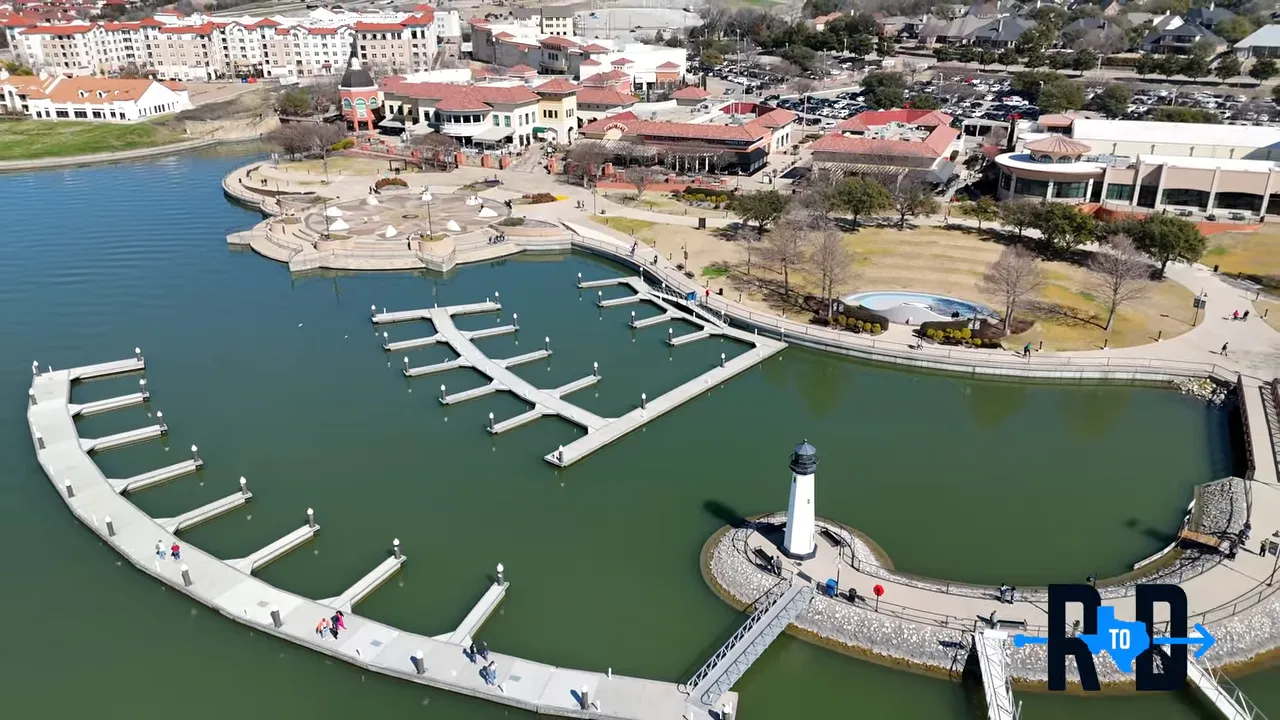 Drone aerial of Rockwall Harbor showing curved docks, lighthouse and the waterfront park near Rockwall, Texas.