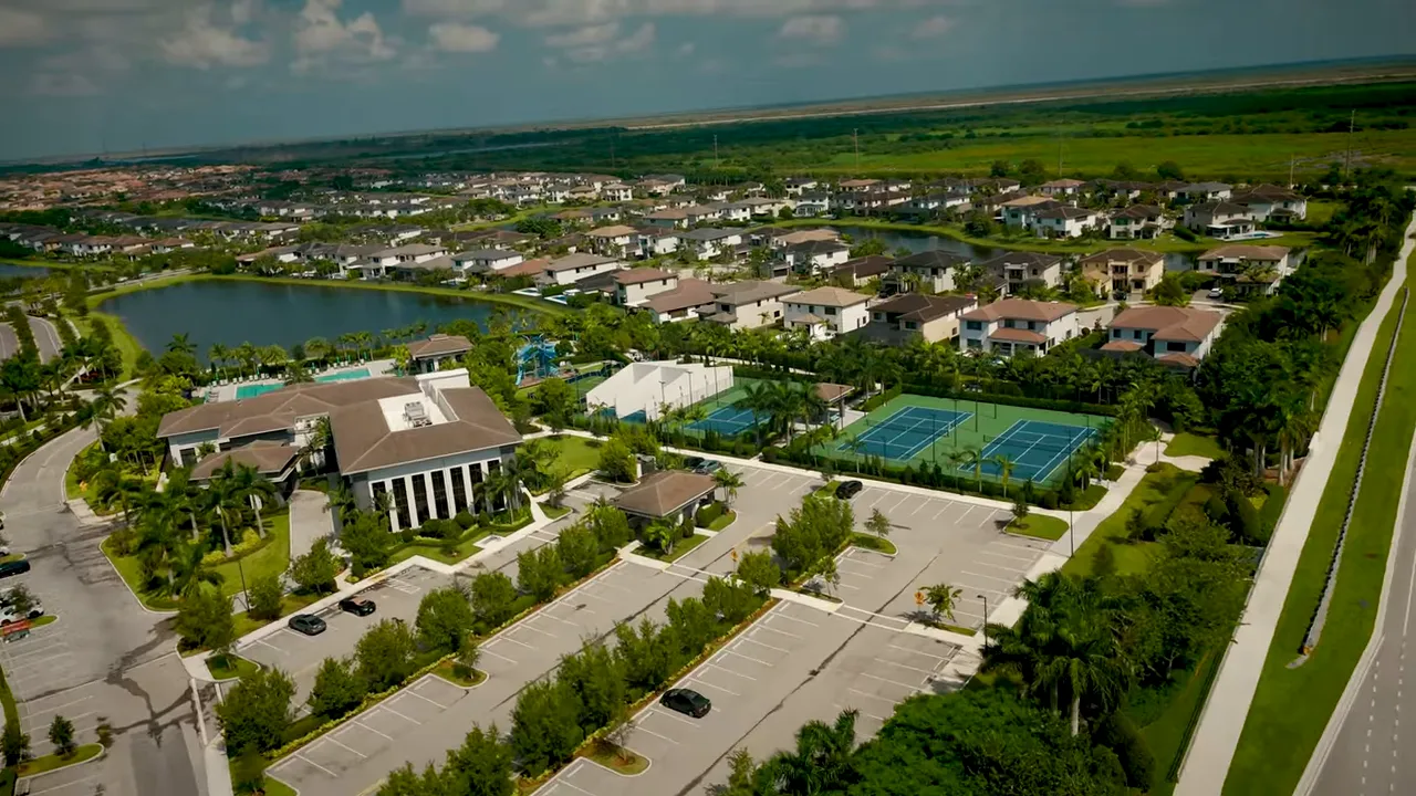 Aerial view of a master-planned suburban community with clubhouse, swimming pool, tennis courts and single-family homes