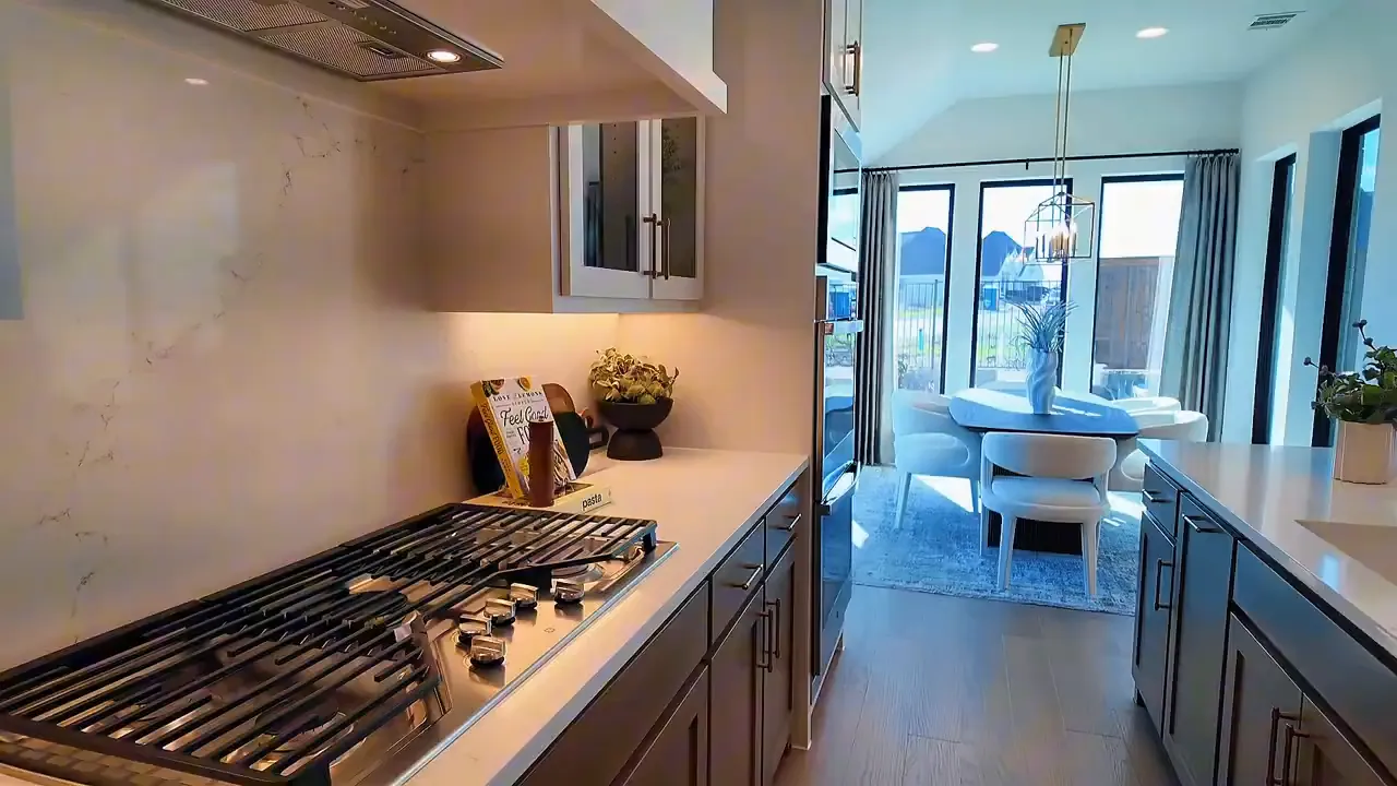 Gourmet kitchen with five-burner gas cooktop and doors to the patio in Meraki by Perry Homes Forney TX