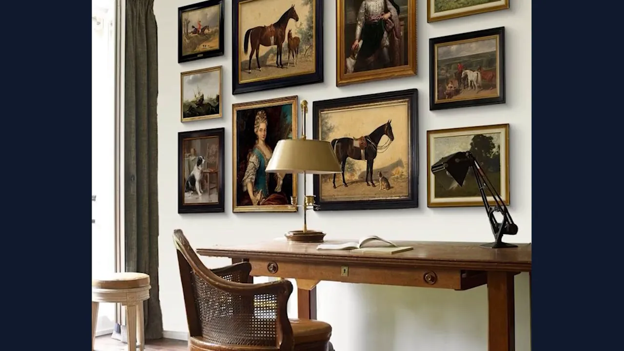 Wall gallery of framed artwork above a desk with lamp